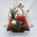 ブリキ製の傾斜スクエア鉢に鉢花で生花アレンジ風に仕上げました。 リビングなどに飾るのにピッタリな商品です。